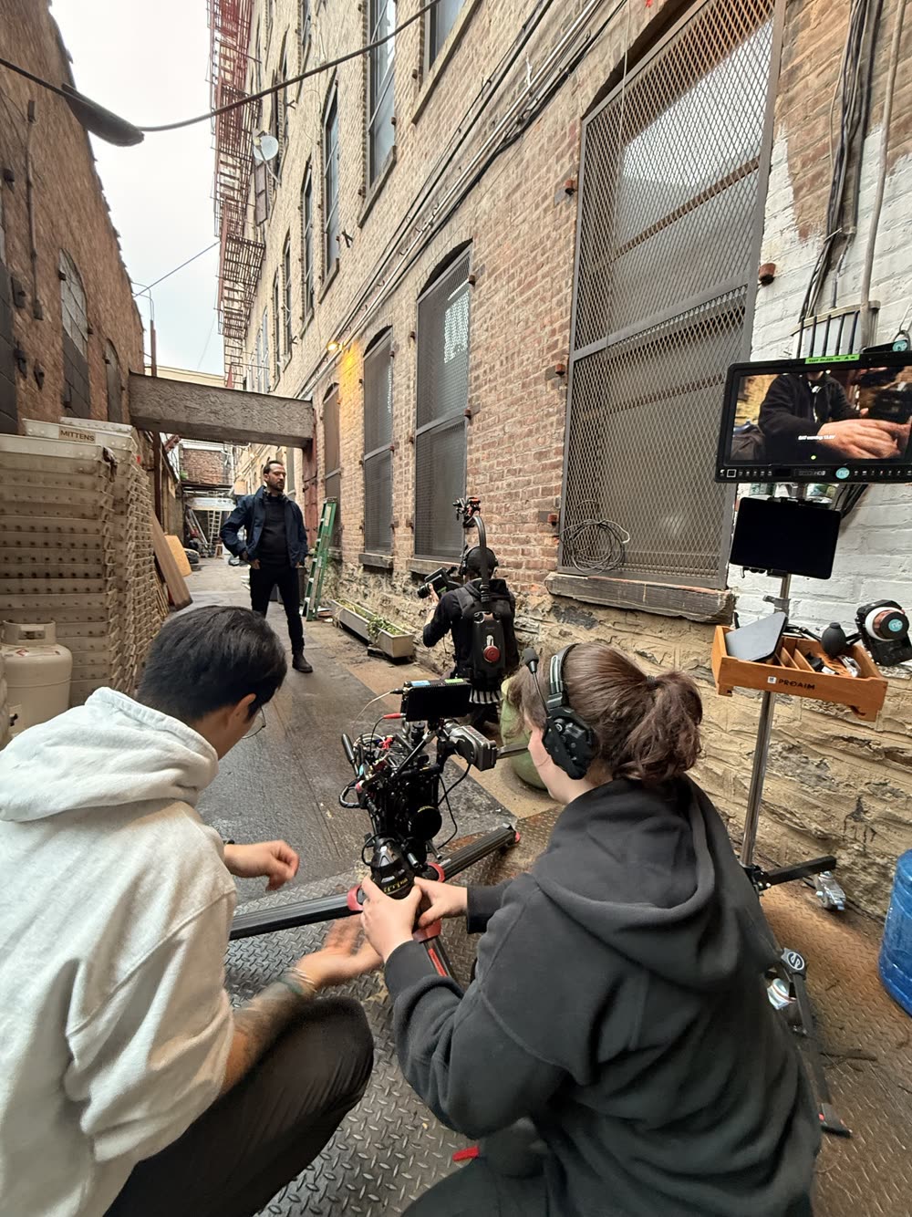 Camera team on a dolly and a Steadicam operator filming in a brick alley
