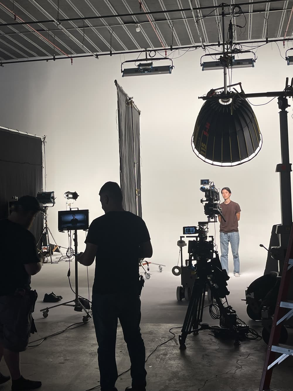 Studio stage with a large softbox, cinema camera and crew in silhouette